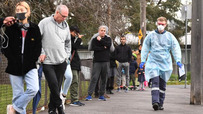 A health worker (R) takes details as people queue for coronavirus testing in a park in the Melbourne suburb of Brunswick West. Picture: AFP