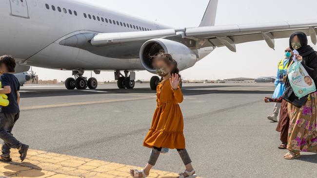 An Afghanistan evacuee waves while boarding a flight to Australia, from the Australian Defence Force's main operating base in the United Arab Emirates. Picture: ADF