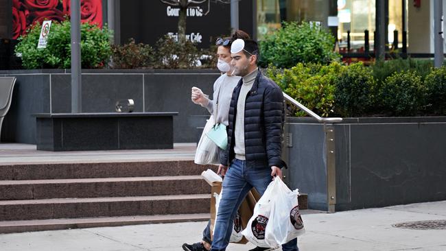 People wearing protective masks while smoking last week in New York, the epicentre of the coronavirus pandemic in the US. Picture: Getty Images.