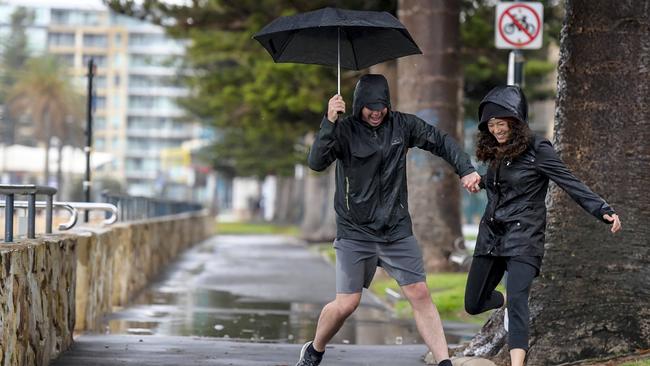 Newly-engaged couple Simon Baldock and Candice Davis decided to walk in the rain at Glenelg. Picture: Roy VanDerVegt.