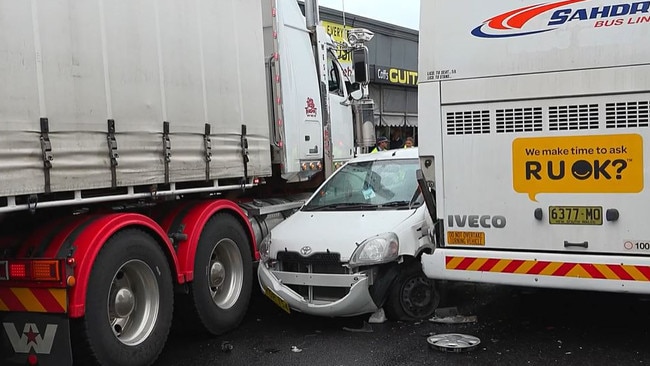 Watch: Close call for woman as car wedged between truck, bus