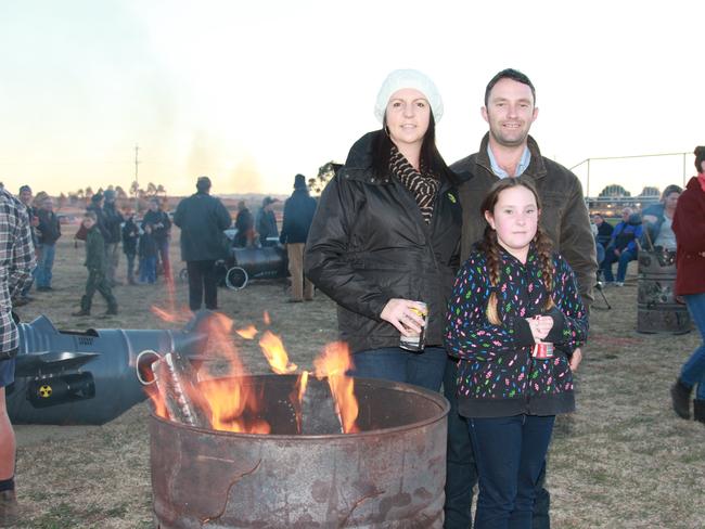 Bec Burville and John and Elizabeth Kunkel warm up around one of the fire drums at the Killarney Bonfire and Fire Drum Night on Saturday, July 19, 2014.