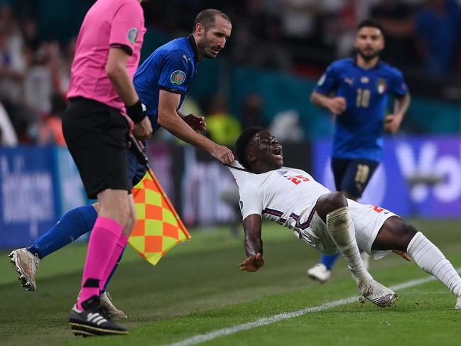 Italy's defender Giorgio Chiellini (C) fouls England's midfielder Bukayo Saka (R) during the UEFA EURO 2020 final football match between Italy and England at the Wembley Stadium in London on July 11, 2021. (Photo by Laurence Griffiths / POOL / AFP)