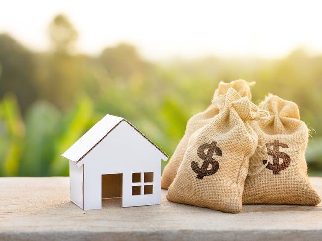 Loan and House concept. Money bags put near house on woodle desk at sunset and green nature background