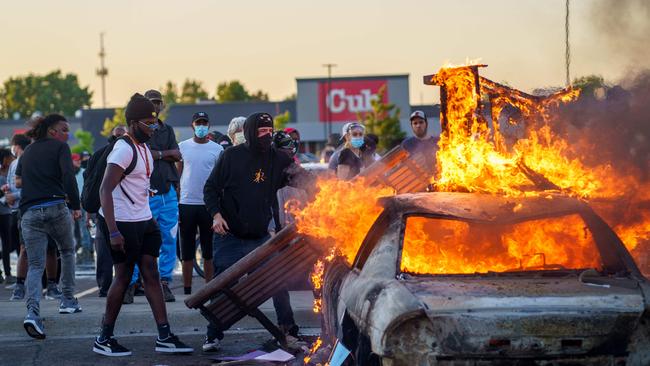 Protesters throw objects onto a burning car in Minneapolis, Minnesota, during a Black Lives Matter demonstration over the death of George Floyd. Picture: AFP