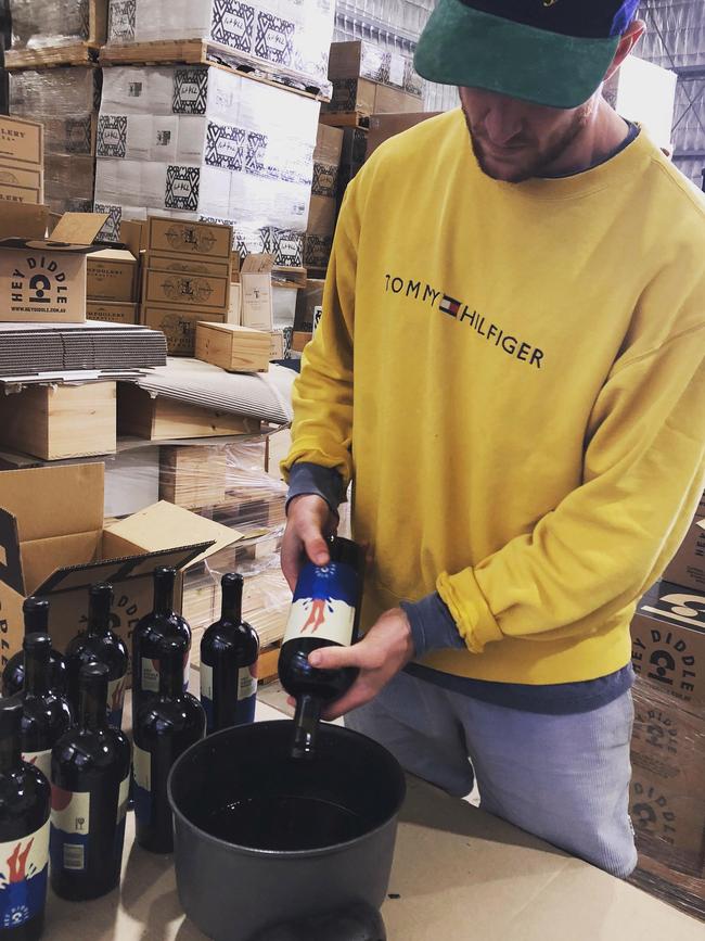 Off-field: Port Defender Tom Jonas uses hot wax during the week to seal bottles of the Hey Diddle Wines’ Shiraz. Picture: Supplied