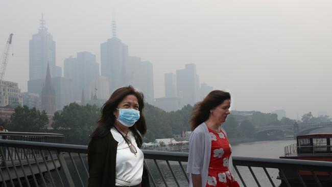 People wear breathing masks to protect themselves from a thick smoke haze that hangs over Melbourne from the bushfires, January 14, 2020. Picture: AAP