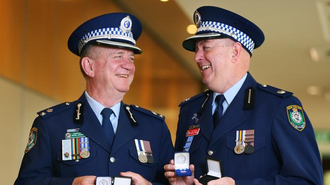 Superintendent Peter Lennon and Chief Inspector Stephen hold the two clasps awarded to them for 35 years of service in the police force. Picture: AAP Image/Angelo Velardo