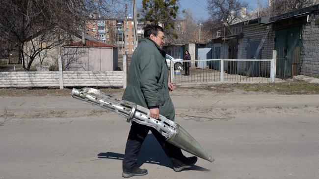 A man carries out a fragment of cluster rocket exploded at a clinic building after the Russian attack on the 30th day of the Russian invasion of Ukraine in the northeastern city of Kharkiv. Picture: AFP