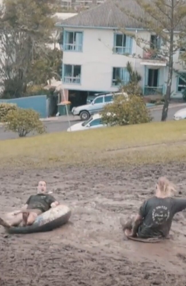 The young men were sliding down Kirra Hill, which was blocked off by Council after heavy rainfall and flooding. Pic: TikTok.