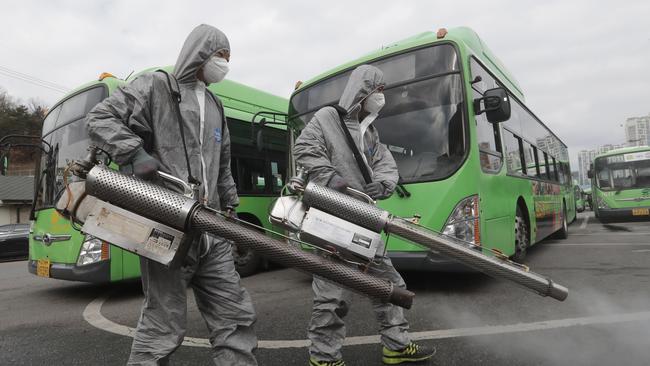 Workers wearing protective suits spray disinfectant as a precaution against the coronavirus at a bus garage in Seoul, South Korea. Picture: AP