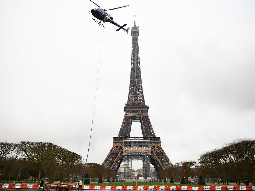 TOPSHOT - This photograph taken in Paris on March 15, 2022 shows a new antenna installed by a Eurocopter AS355N Ecureuil 2 at the top of the Eiffel Tower. (Photo by Christophe ARCHAMBAULT / AFP)