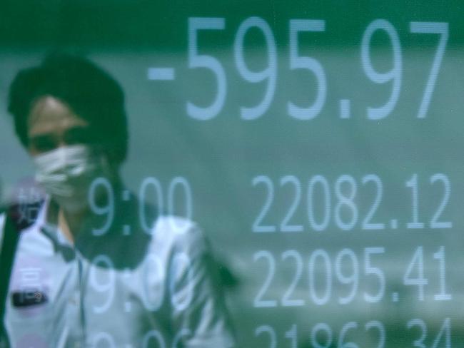 A pedestrian is reflected on an electronic quotation board displaying share prices of the Tokyo Stock Exchange (C) in Tokyo on June 12, 2020. (Photo by Kazuhiro NOGI / AFP)