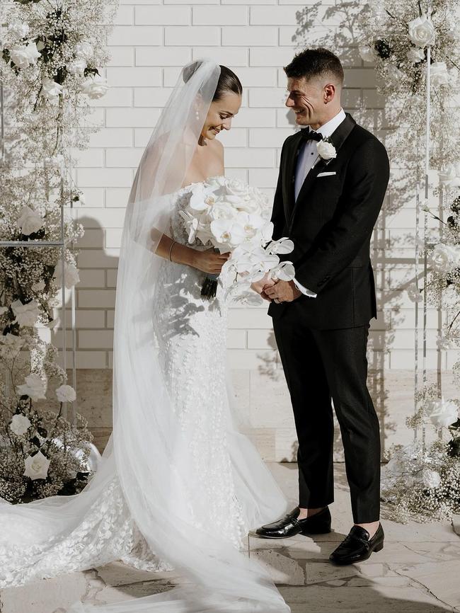 The couple exchanged vows against a backdrop of a whitewashed wall adorned with floral arrangements. Photo: Instagram.