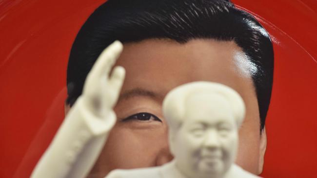 A decorative plate featuring an image of China's President Xi Jinping is seen behind a statue of late communist leader Mao Zedong. Picture: AFP