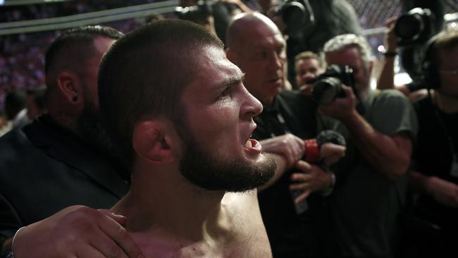 Khabib Nurmagomedov is held back outside of the cage after beating Conor McGregor