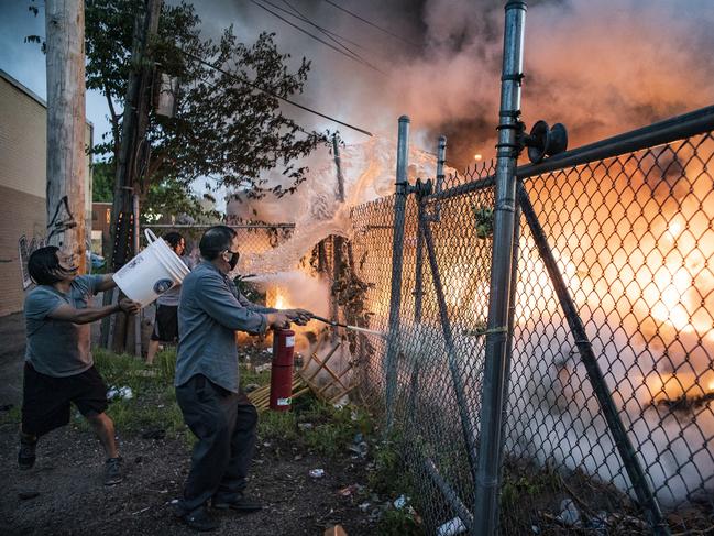 Residents put out a car fire near Lake Street in Minneapolis. Picture: Richard Tsong-Taatarii/Star Tribune via AP