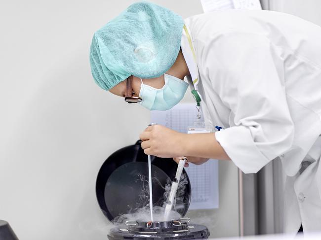 Side view of scientist handling oocytes and sperm for cryopreservation to be stored in liquid nitrogen.