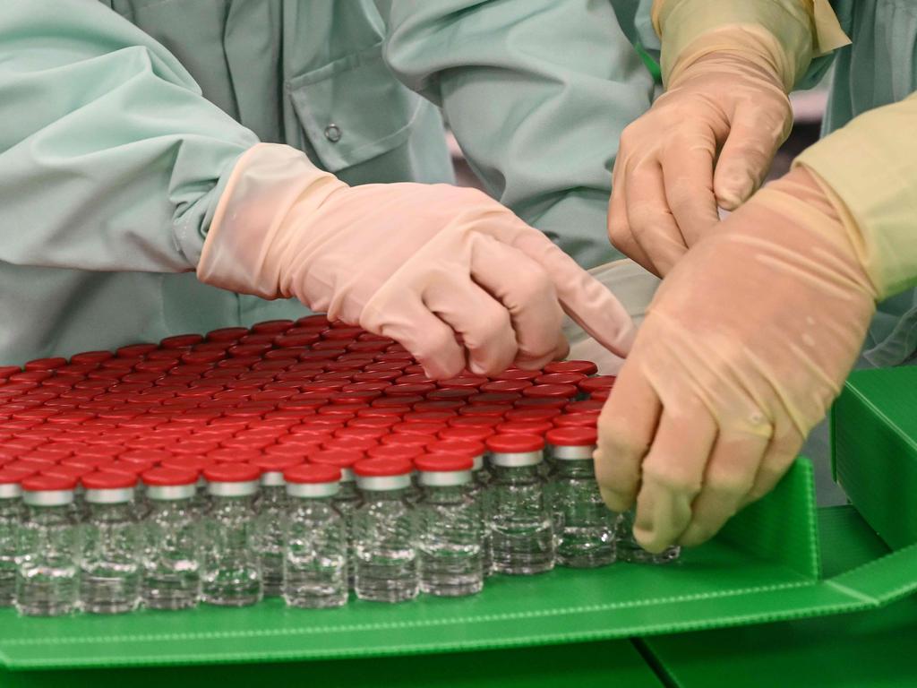 Laboratory technicians handle capped vials of the developing AstraZeneca vaccine. Picture: Vincenzo Pinto / AFP