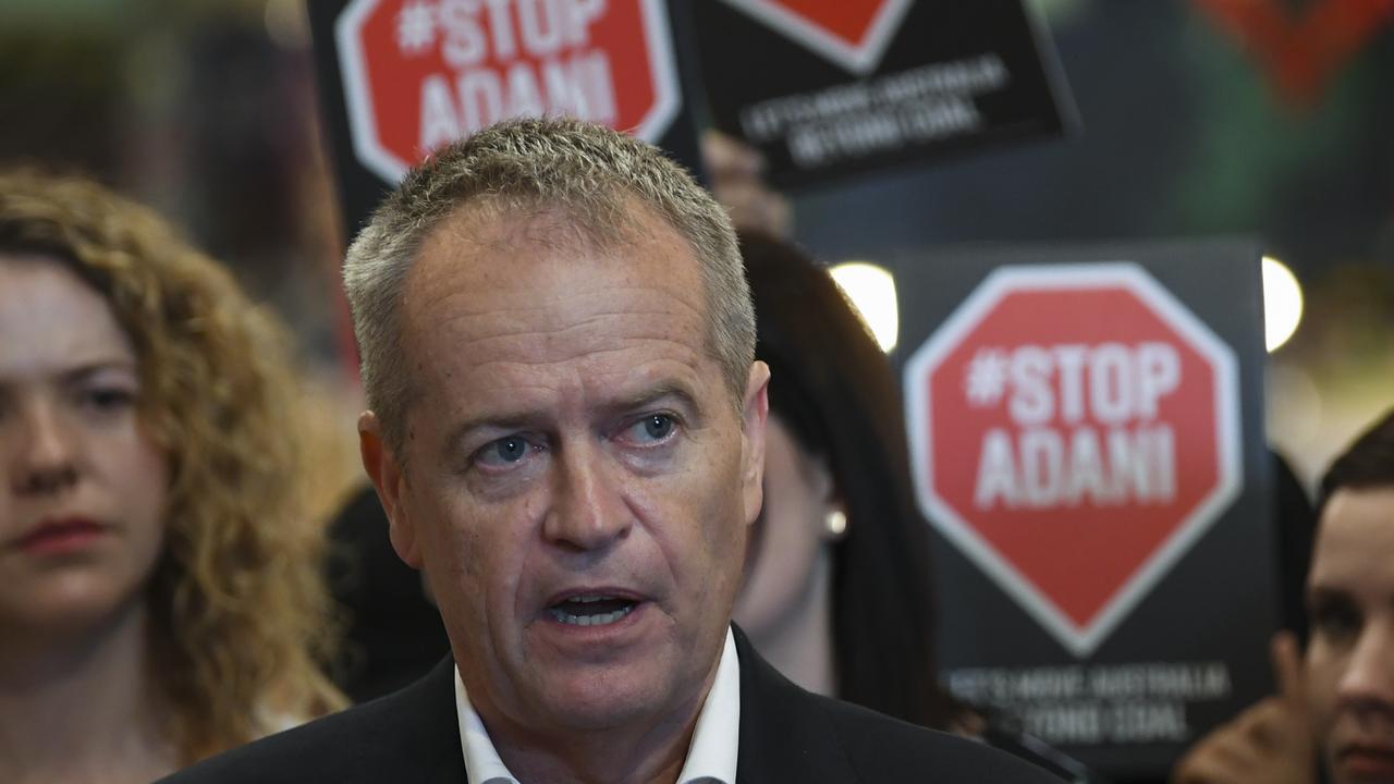 Bill Shorten speaking to the media yesterday, framed by protesters’ signs. Picture: AAP 