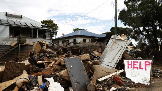 Help written on a growing pill of destroyed household items by the flooding Wilsons River, outside a home on Elliott Rd in South Lismore. Picture: Jonathan Ng