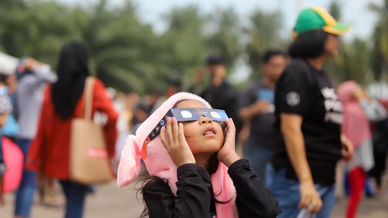 A girl uses solar filter glasses to watch a rare ‘ring of fire’ solar eclipse in Tanjung Piai, Malaysia in 2019. Picture: Sadiq Asyraf/AFP