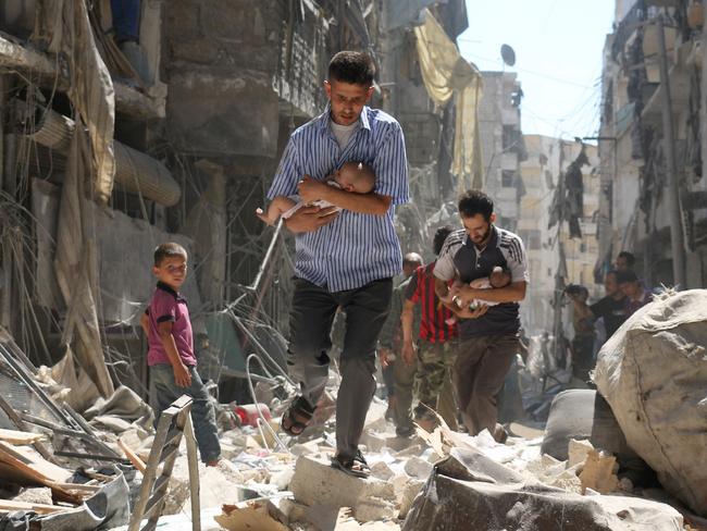 AFP PICTURES OF THE YEAR 2016 Syrian men carrying babies make their way through the rubble of destroyed buildings following a reported air strike on the rebel-held Salihin neighbourhood of the northern city of Aleppo, on September 11, 2016. Air strikes have killed dozens in rebel-held parts of Syria as the opposition considers whether to join a US-Russia truce deal due to take effect on September 12. Photo: AFP/ AMEER ALHALBI