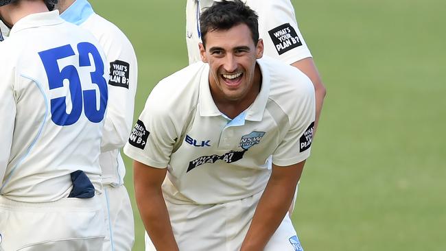 Mitchell Starc laughs as he celebrates a wicket with teammates.