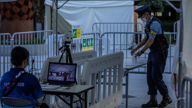 A police officer applies hand sanitiser as a staff member monitors peoples’ temperatures with a scanner at the entrance to Tokyo Metropolitan Gymnasium, the Olympics venue for table tennis. Picture: Getty