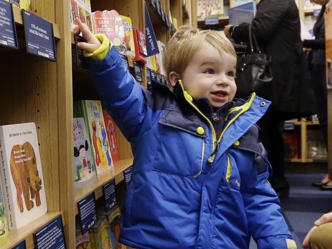 Customer Michael Wallenfels looks at children's books with his son Henry, 2, at the opening day for Amazon Books, the first brick-and-mortar retail store for online retail giant Amazon, Tuesday, Nov. 3, 2015, in Seattle. The company says the Seattle store, coming two decades after it began selling books over the Internet, will be a physical extension of its website, combining the benefits of online and traditional book shopping. Prices at the store will be the same as books sold online. (AP Photo/Elaine Thompson)