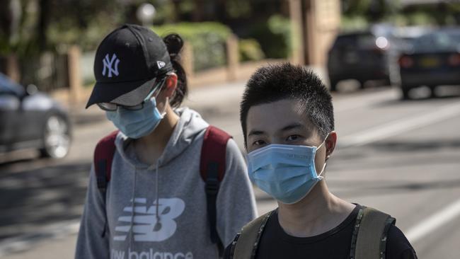 Members of the public are pictured in face masks outside Epping High School. Picture: Brook Mitchell