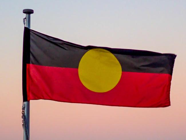 The Australian Aboriginal flag flies at Bondi Beach, Sydney at sunset in winter on 16 June 2023. In the background is the Pacific Ocean.