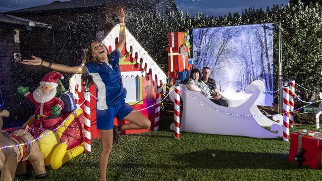 Sue and Pete Black with granddaughter Kira Suey in the foreground enjoying the snow machine. Christmas lights at 60 Gouldson Drive. Thursday, December 9, 2021. Picture: Nev Madsen.