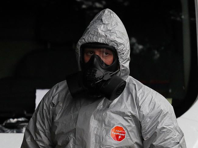 Military personnel wearing protective coveralls work to remove a vehicle as part of the ongoing investigation in connection with the incident. Picture: AFP