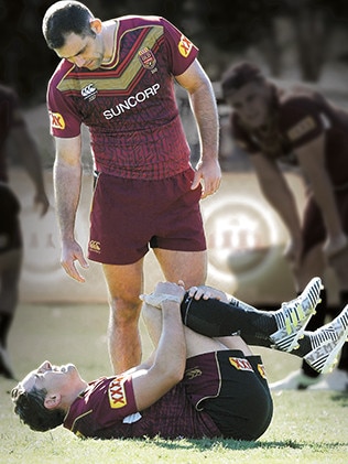 Cameron Smith comes to Billy Slater’s aid after the fullback rolled his ankle at training. Photo: AAP