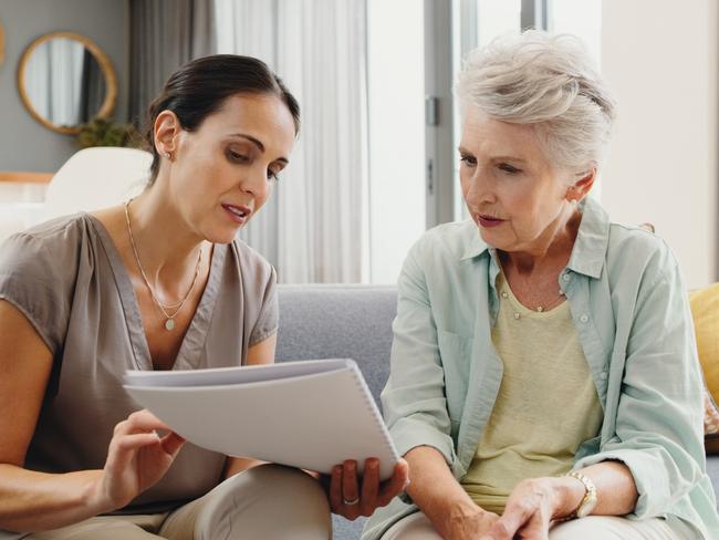 Caregiver talking to senior woman about insurance, support with finance documents and help reading retirement paperwork on the sofa in home. Girl helping elderly person with Alzheimer care at house