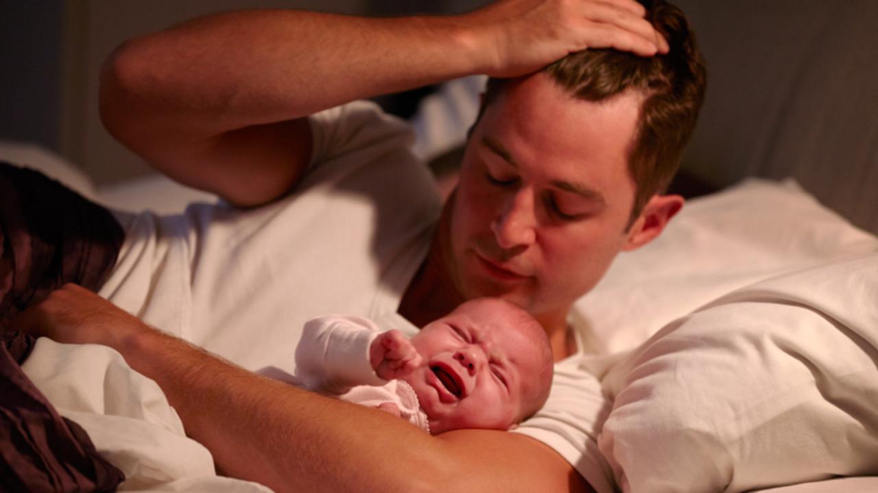 Father Lying In Bed With Crying Baby Daughter