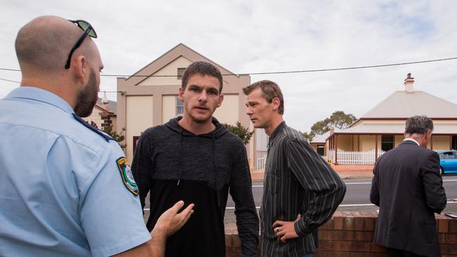 Shane Whitall (right) and a friend speak with police and the media outside court.