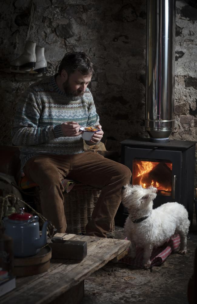 Peter MacQueen enjoys his Scotch broth by the fire with his West Highland Terrier, Seòras, at Guardswell Farm in Perthshire, Scotland. Picture: Susie Lowe/Pink Lady® Food Photographer of the Year