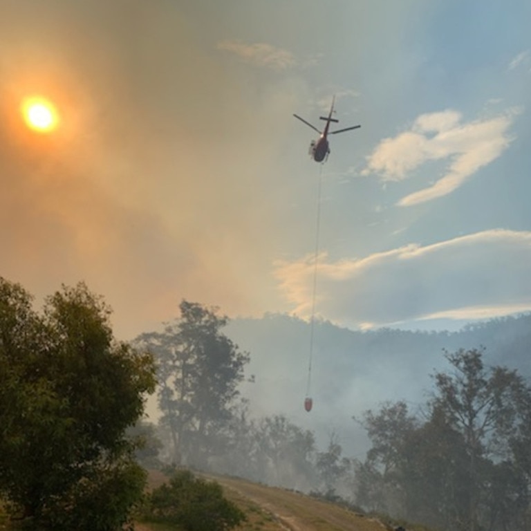 A helicopter in action as heavy smoke shrouds the sun from a fire at Moss Beds Rd, Lachlan. Picture: SUPPLIED