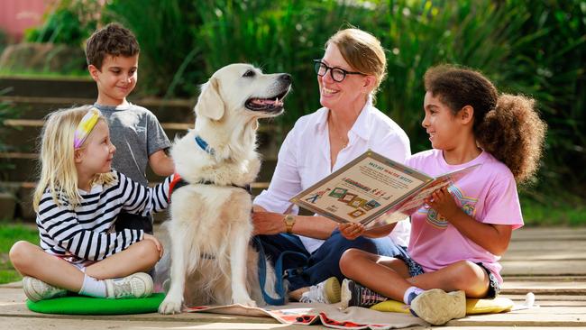 Leonille Senfft von Pilsach, 5, Darris Etemad, 5, and Mina Buschhaus, 5, with Nicole Rosenthal and her golden retriever, Lotti, a volunteer with the Story Dogs Reading Program, at the German International School, Terry Hills, Sydney. Picture: Justin Lloyd