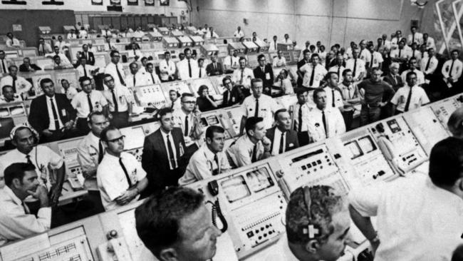 Members of the Kennedy Space Center control room team rise from their consoles to watch the liftoff of the Apollo 11 mission on July 16, 1969.