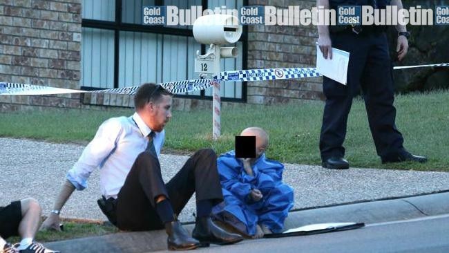 A young boy is comforted at the scene of an Upper Coomera double murder. Photo: Glenn Hampson