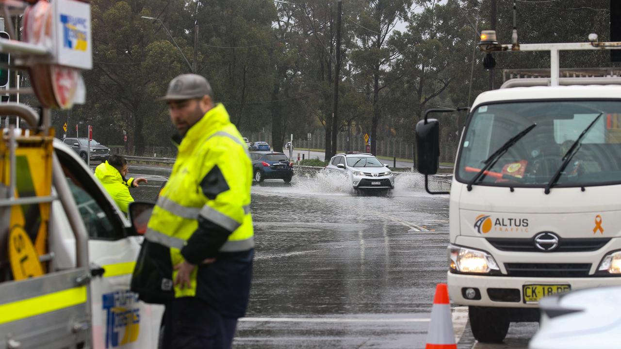 Traffic controllers on Henry Lawson Drive, which has been closed due to flooding between Milperra Road and the Hume Highway over the Georges River. Picture: Gaye Gerard