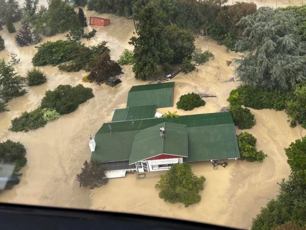 People stranded preparing to be air lifted from their rooftop by a military helicopter in the Esk Valley, near the North Island city of Napier. Picture: New Zealand Defence Force / AFP