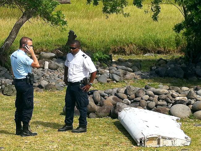 (FILES) This file photo taken on July 29, 2015 shows a policeman and a gendarme standing next to a piece of debris later identified from missing Malaysia Airlines plane MH370, found on the French Indian Ocean island of La Reunion. Missing Malaysian flight MH370 is almost certainly not in the current search zone in the remote Indian Ocean but could be further north, officials said on December 20, 2016. No trace has been found in the massive undersea hunt off Australia for the jet that disappeared en route from Kuala Lumpur to Beijing on March 8, 2014, carrying 239 passengers and crew.   / AFP PHOTO / Yannick PITOU