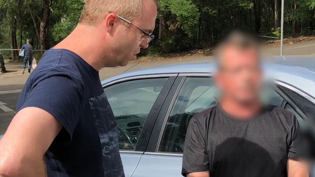 A policeman speaks with Bakic-Kaindl (face obscured) at his arrest. Picture: NSW Police