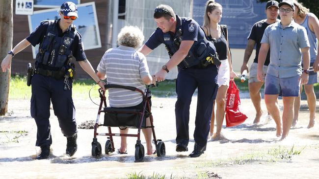 Police help a disabled person to safety from a flooded park. Picture: AAP