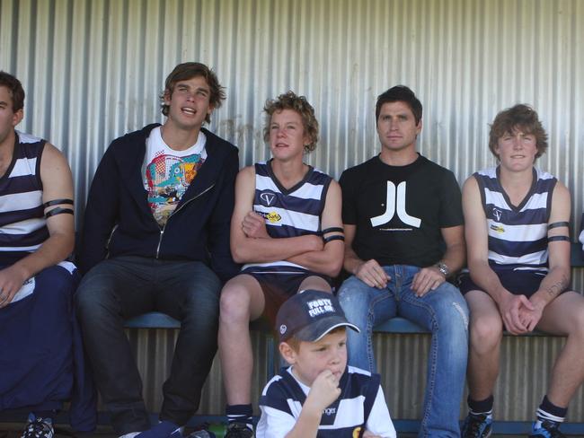 Shane Crawford and Tom Hawkins sit on the bench with Finley players