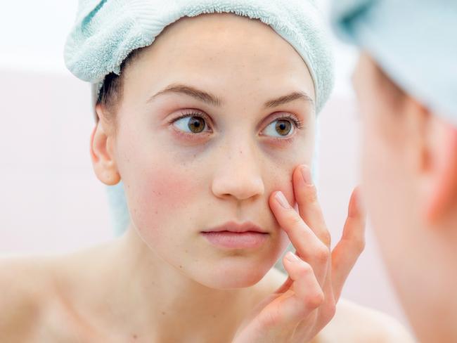 Young woman portrait in the mirror of her bathroom after taking shower.